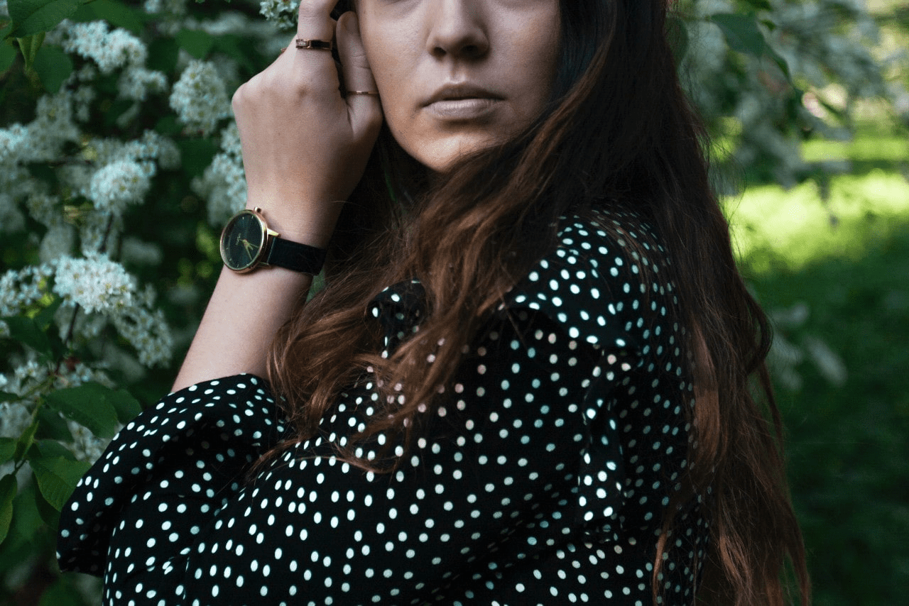 A woman wearing a black strap and gold dial Shinola watch outside 