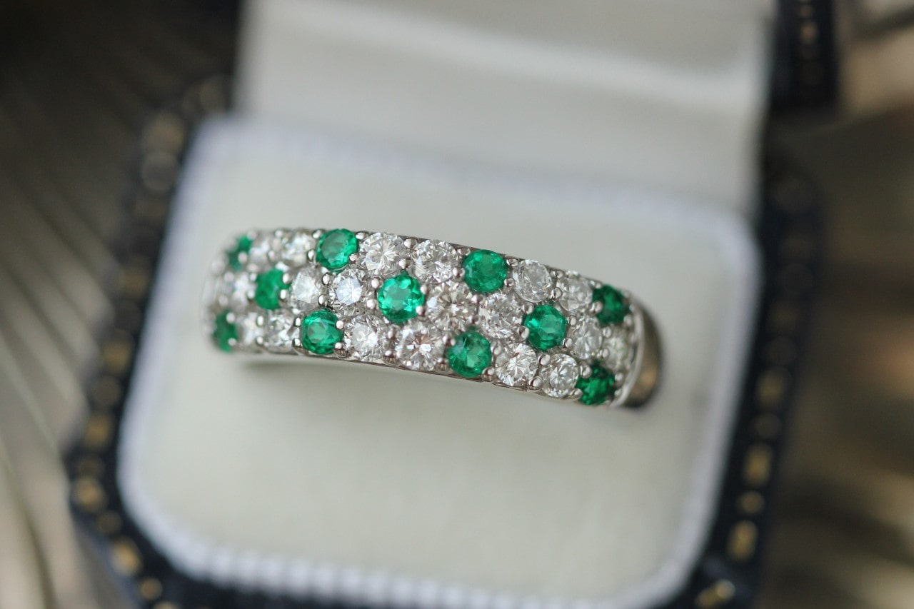 a white gold wedding band featuring round cut diamonds and emeralds