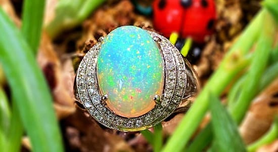 a white gold fashion ring featuring a double diamond halo and a large opal