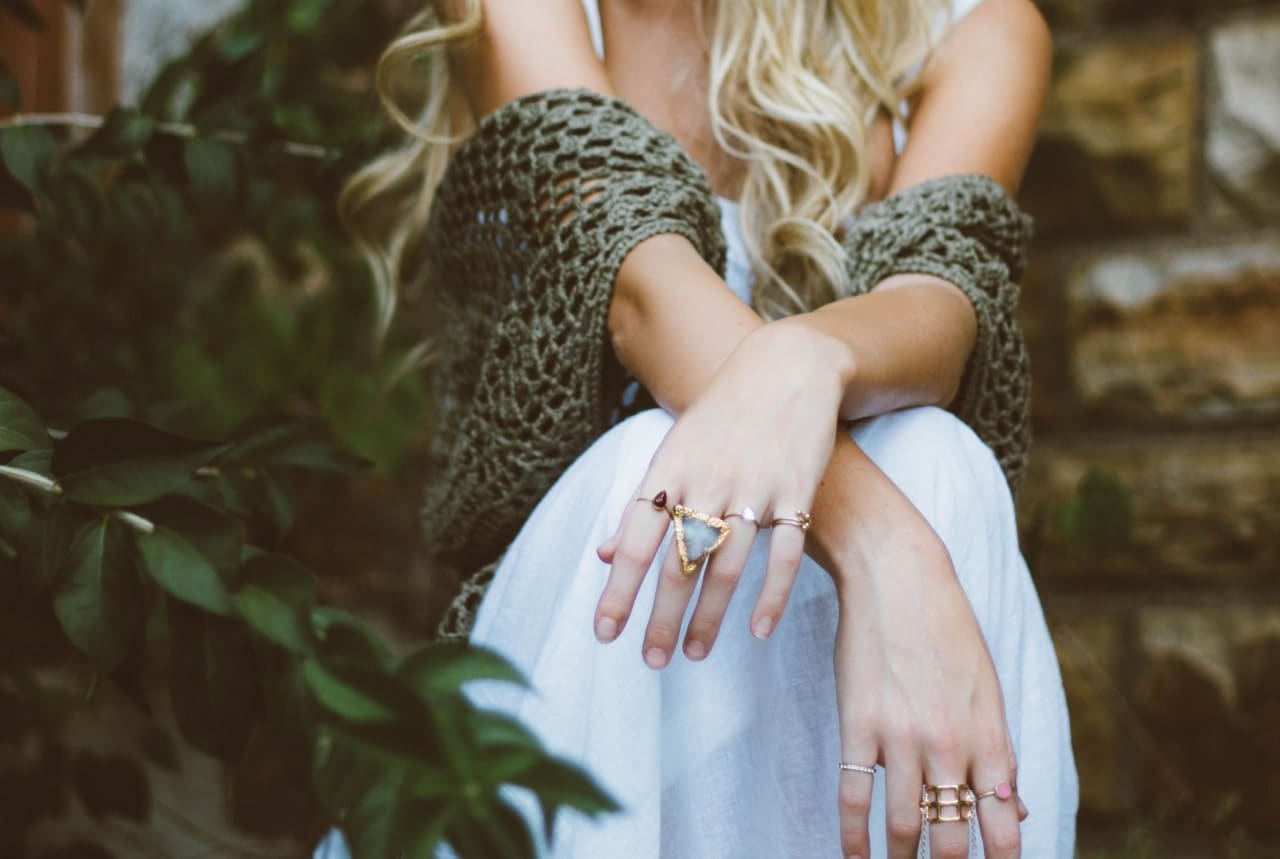 A fashionable young woman sports an eccentric, geometric-design aquamarine fashion ring among an assortment of different rings