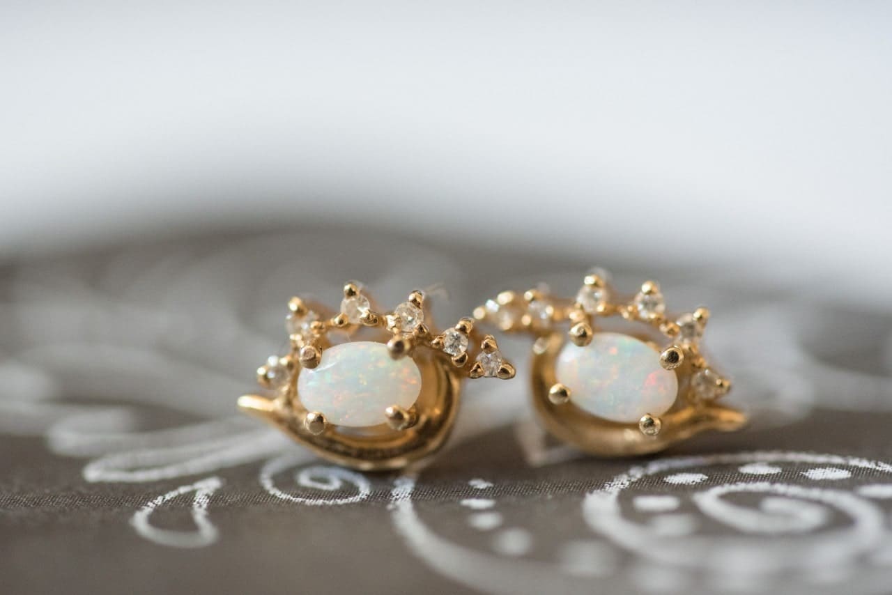 A pair of oval-cut opal stones set in yellow gold stud earrings.