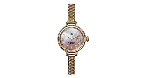 a gold Shinola watch with a mother of pearl dial