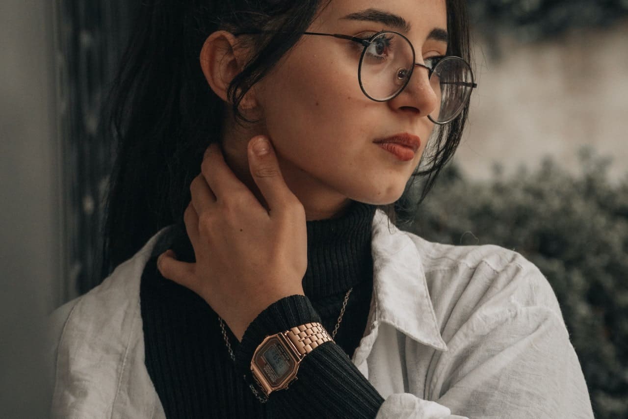 a woman looking off to the side wearing a rose gold digital watch