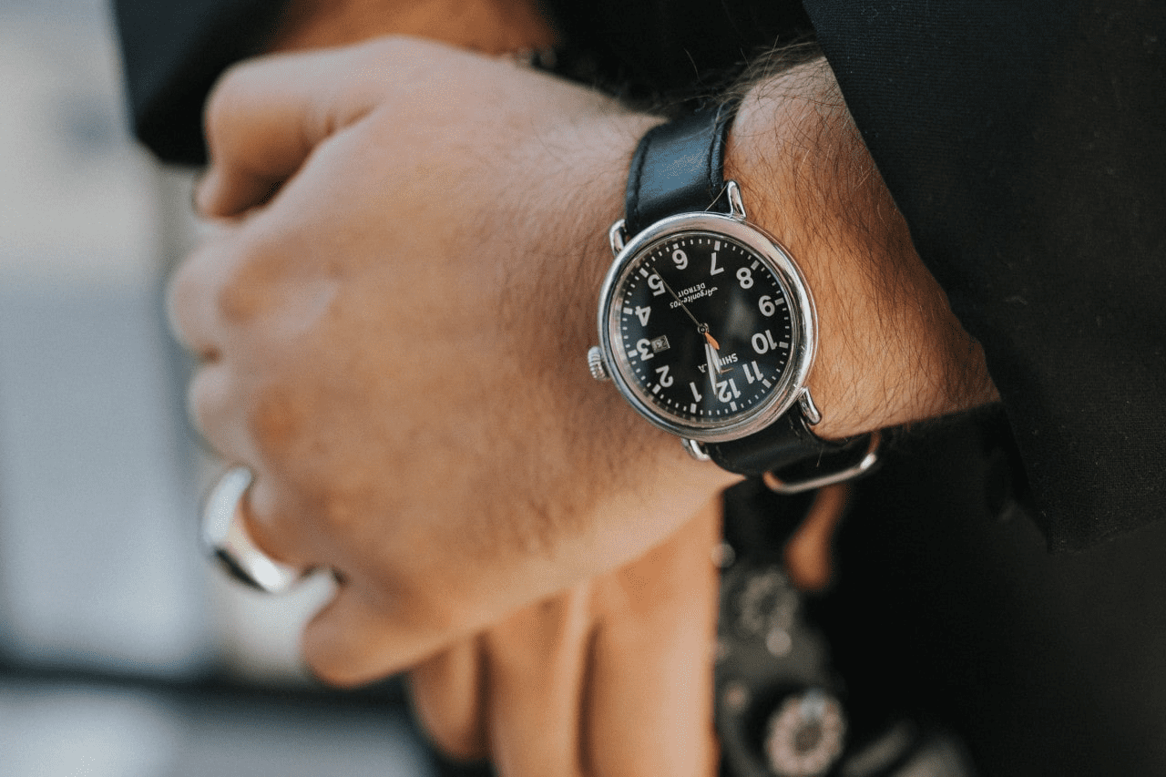 A man wearing an black and silver dialed Shinola watch