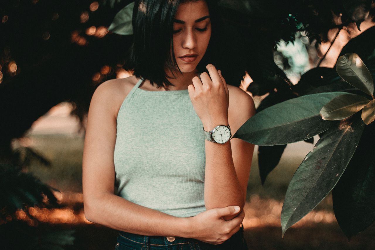a lady standing by foliage and wearing a luxury timepiece