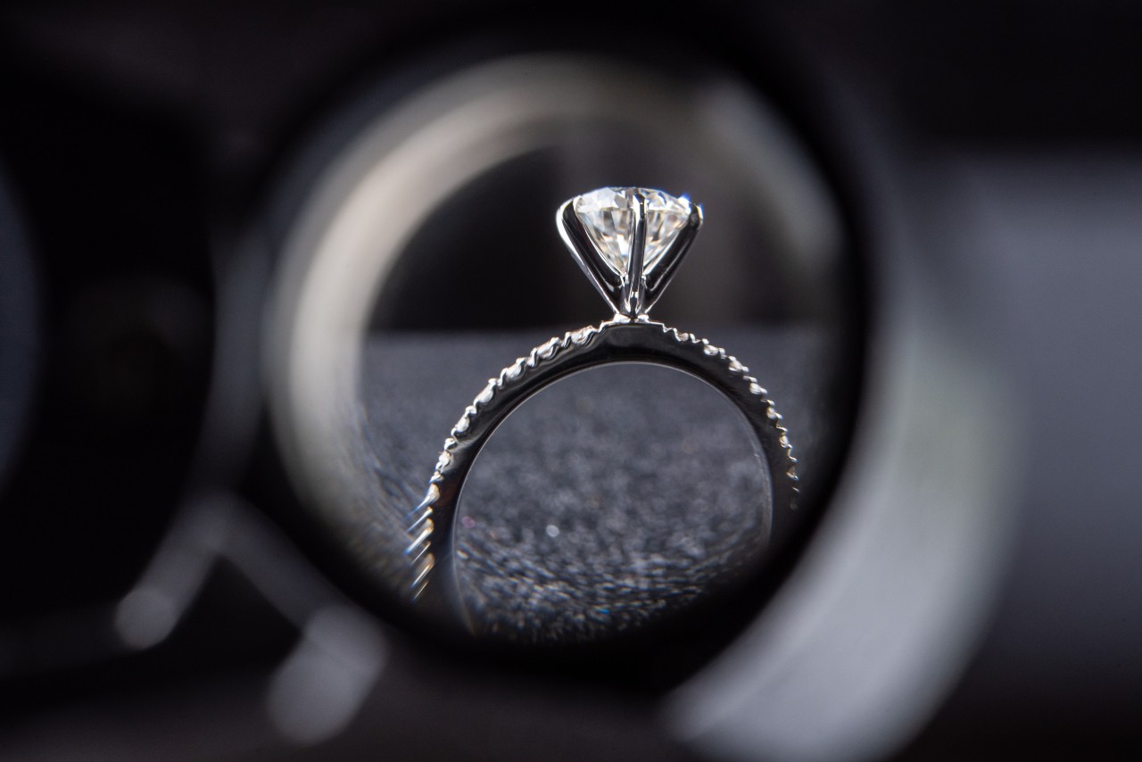 A view of a solitaire engagement ring through a jeweler’s magnifier.