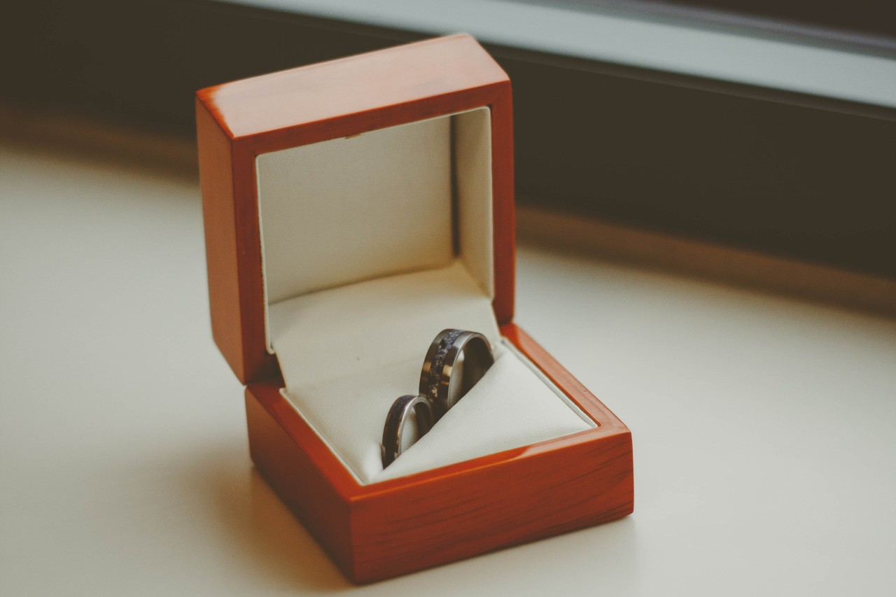 a pair of matching men’s and women’s wedding bands sit in a wooden box.