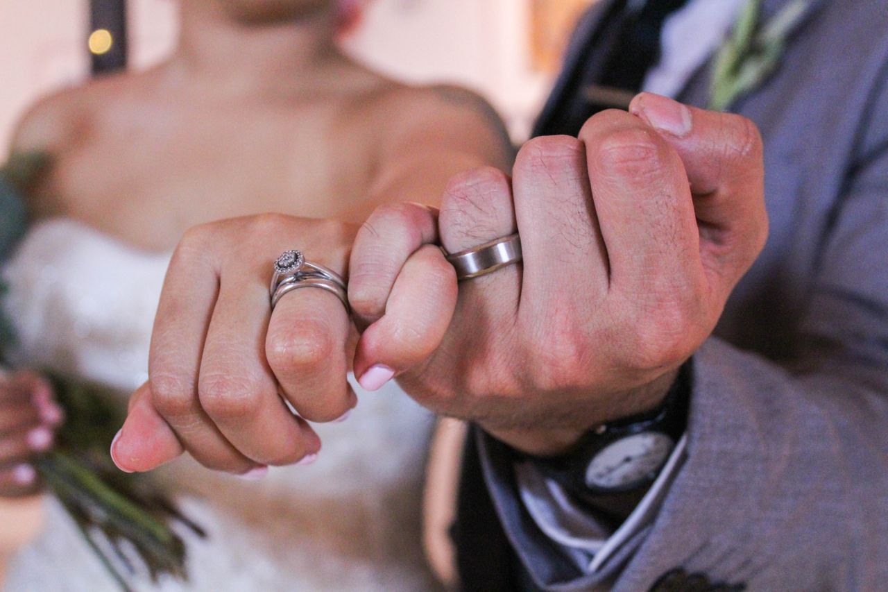 a couple wearing matching platinum wedding rings link pinkie fingers.